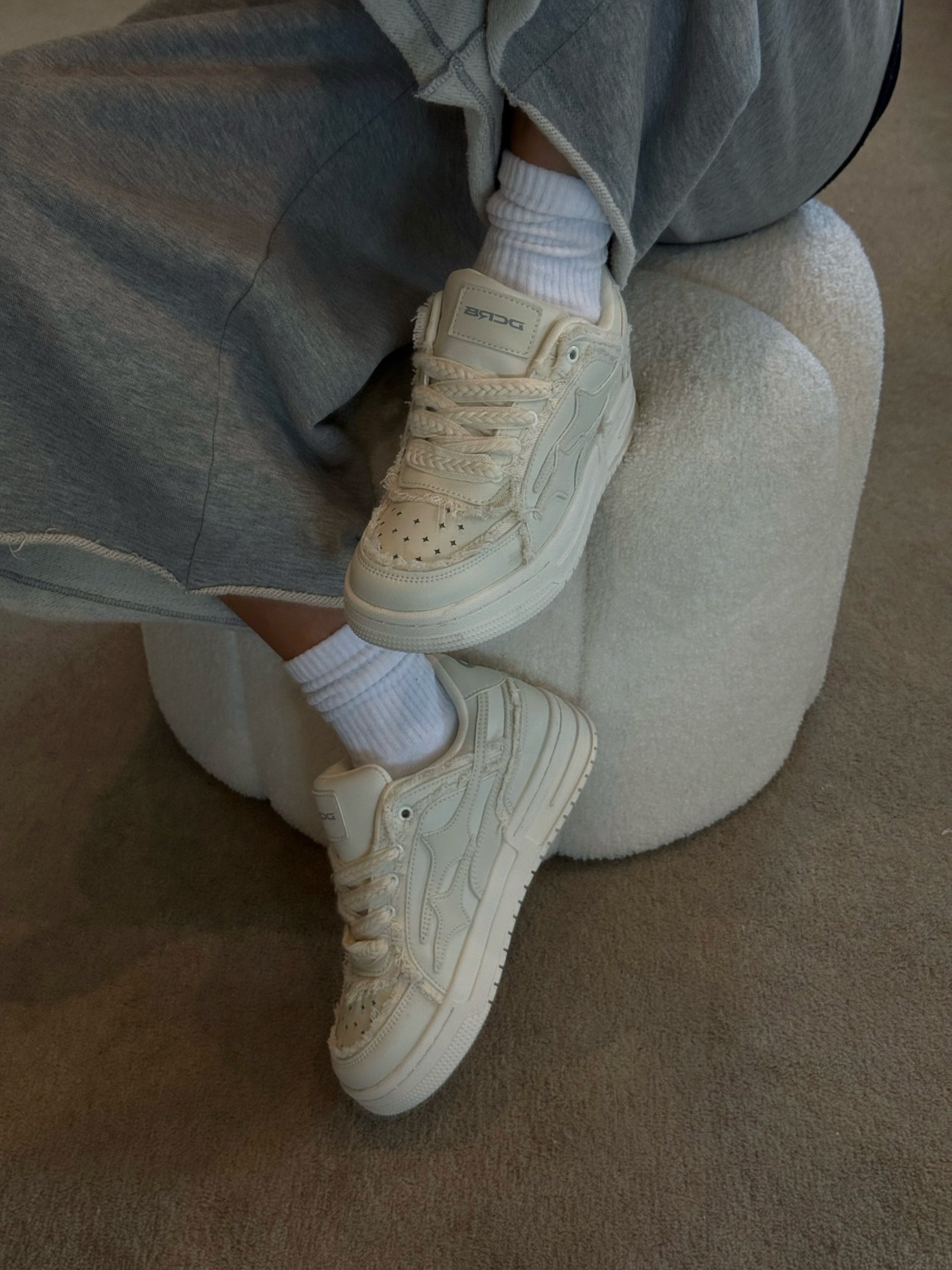 Cream streetwear sneakers showing the lace-up fastening