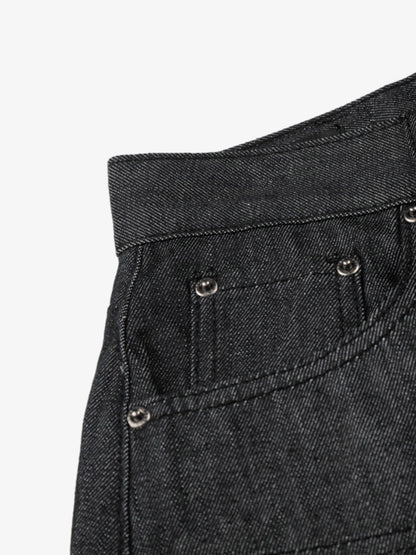 Close-up of black denim shorts with metallic studs and patchwork finish