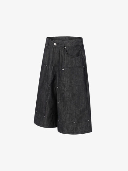 Side view of black denim shorts showing stud detail and patchwork design