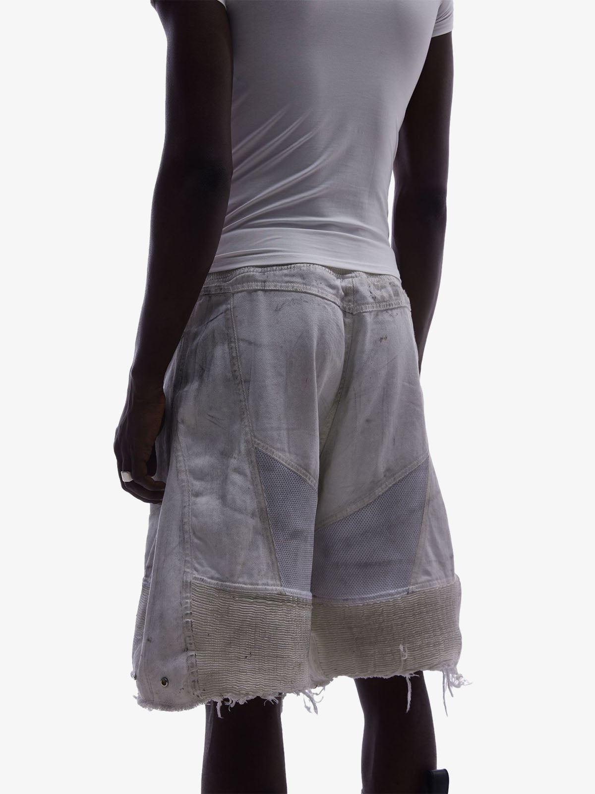 Side view of layered denim shorts showing mesh panel insert and layered waist