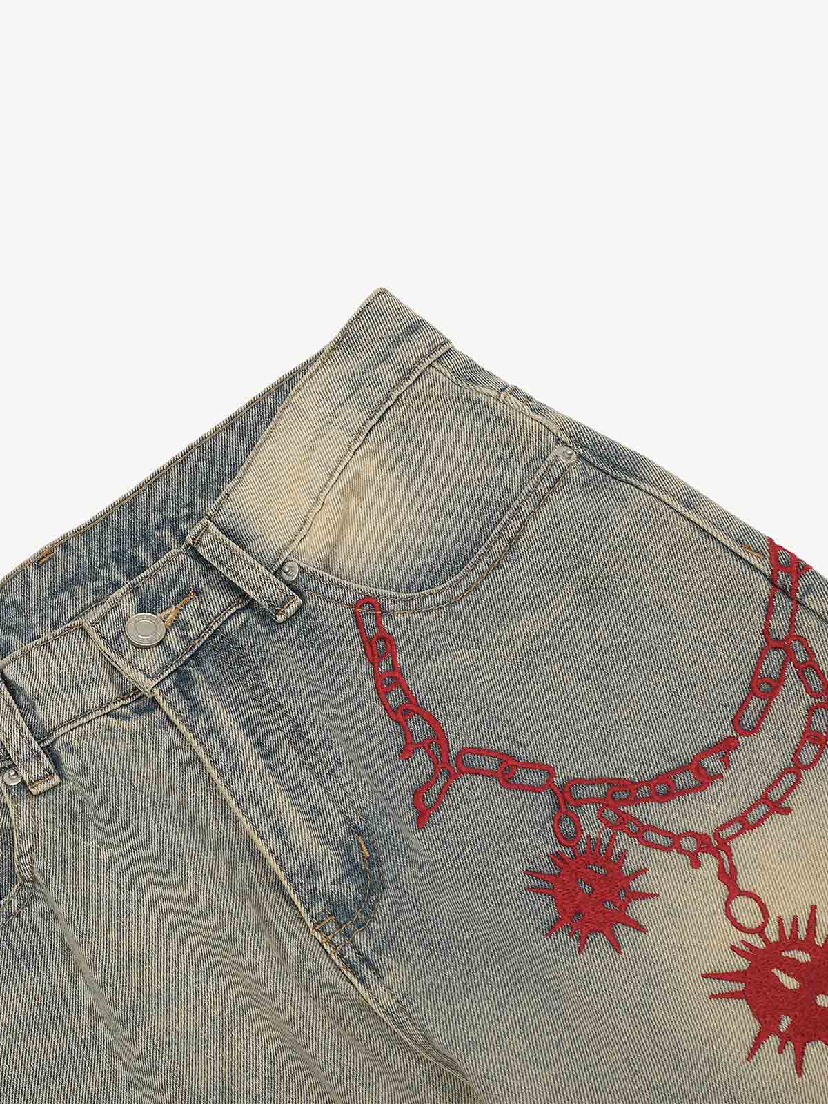 Close-up of red embroidered detail on distressed denim jeans