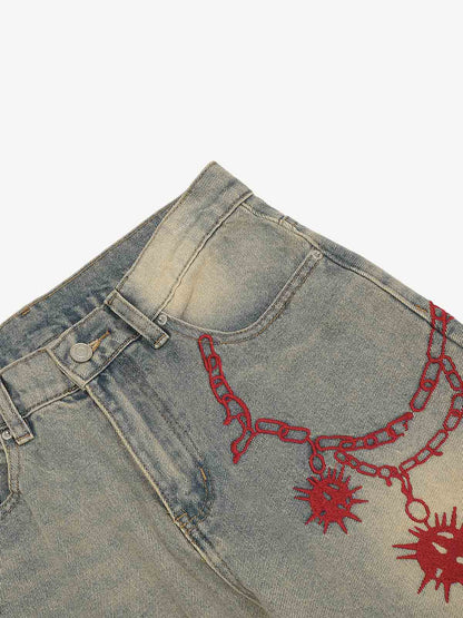 Close-up of red embroidered detail on distressed denim jeans