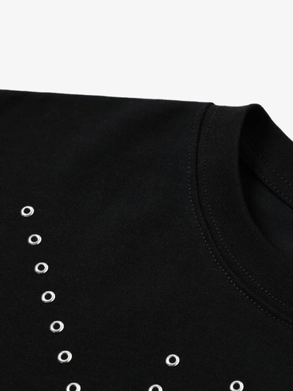 Close-up of silver grommet detail on black cotton T-shirt