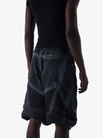 Angled back view of denim shorts with layered construction and mesh panels